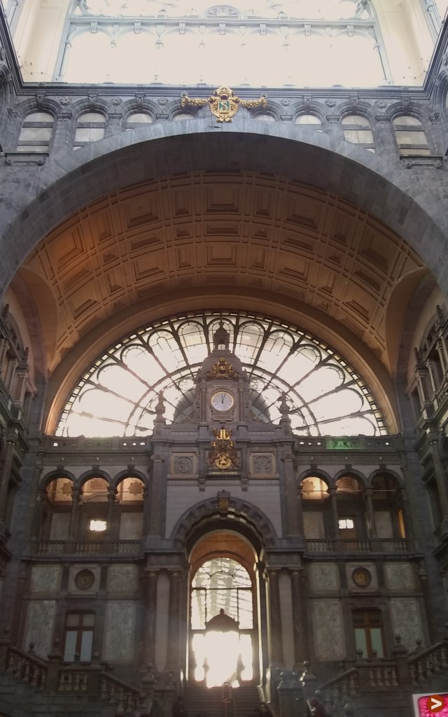 Large, ornate train station entrance with fanned window and a clock